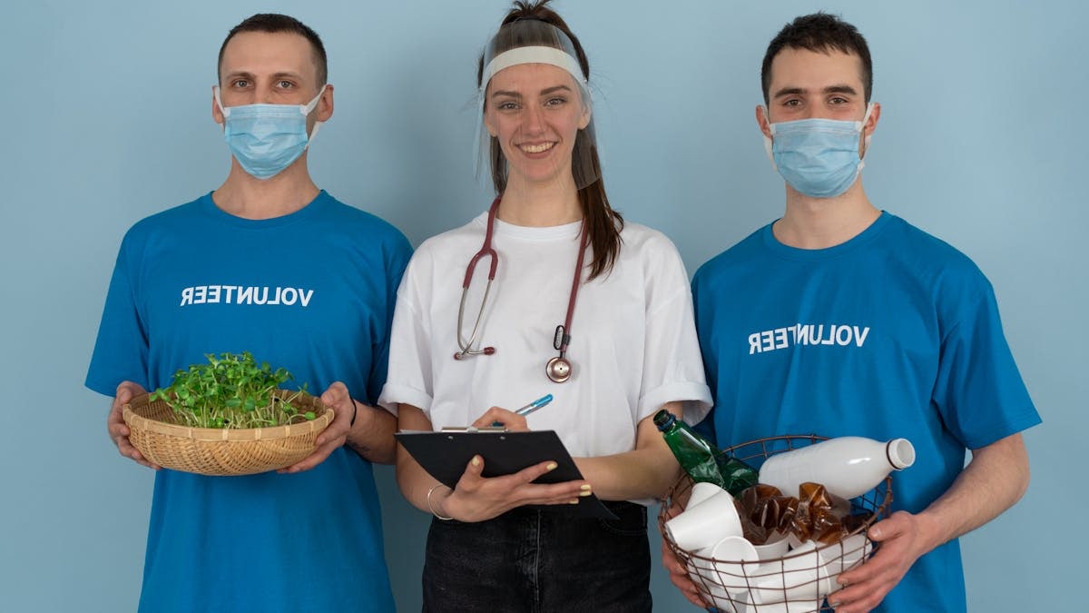 Three volunteers promoting eco-friendly practices with plants and recycling materials.